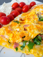 close up omelet with cherry tomatoes and cheese on plate
