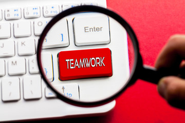 TEAMWORK word written on keyboard view with magnifier glass