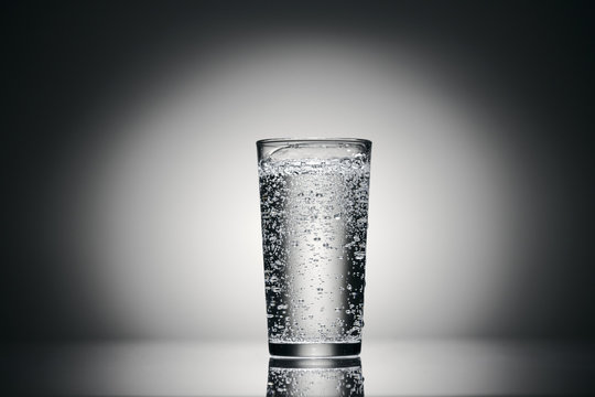 one glass of sparkling water on a dark background