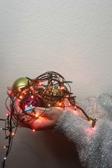 lights in the palms. Women's hands holding a garland. Girl in a white sweater with Christmas lights in her hands, warm Christmas mood, soft focus