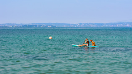 A woman and a dog going to the sea on a sup board
