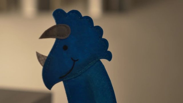 A blue triceratops finger puppet walks in and out of frame