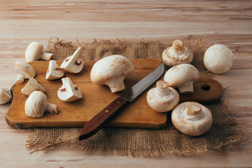 Slicing mushrooms on a wood cutting board. Whole and cut Champignons. 