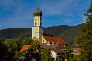 The Catholic Church in the commune of Oberammergau in Bavaria (Germany) against the backdrop of mountains and a cloudy sky.