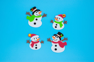 Funny snowmen in red and green scarves and black hats on a blue background
