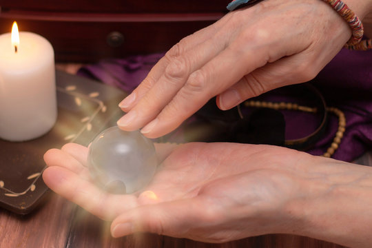 woman fortune teller holds a ball of fate in her hands, a magic ball of predictions. The concept of predicting the future, magic, occultism. Dark background by candlelight