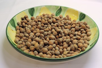 Noisettes dans un plat jaune et vert posé sur un support blanc