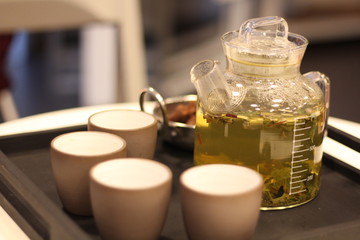 flower tea in a transparent glass teapot and four cups