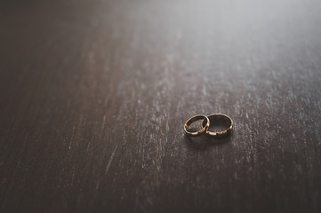 Two wedding rings on a dark wood table.