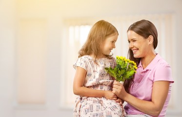 Mother and daughter with bouquet of flowers on blurred background.