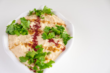 Homemade humus on a white plate with tahini, spicy, olive oil, lemon, parsley and chickpeas. Arabic food, appetizer - Delicious humus. Selective focus.