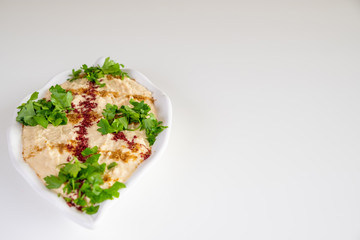 Homemade humus on a white plate with tahini, spicy, olive oil, lemon, parsley and chickpeas. Arabic food, appetizer - Delicious humus. Selective focus.