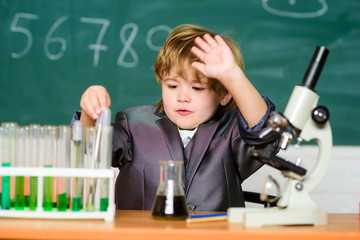 Toddler genius baby. Boy near microscope and test tubes in school classroom. Technology and science concept. Kid study biology and chemistry in school. School education. Explore biological molecules