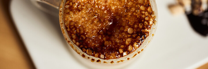 Banner size image of macro photo of hot latte with baked caramel crust. Food concept. Top view close up image of coffee