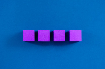 4 purple wooden blocks placed in a row, with copy space, over blue background.