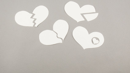 Broken white paper hearts on grey background