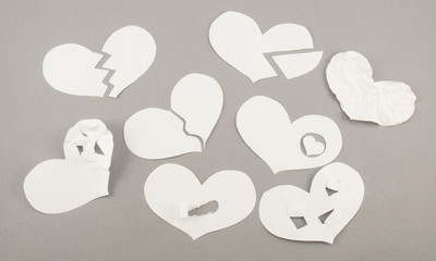 Fototapeta na wymiar Broken white paper hearts on grey background