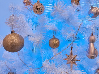 Golden Christmas balls and stars on white branches spruce on a blue background. Background for New Year greetings.