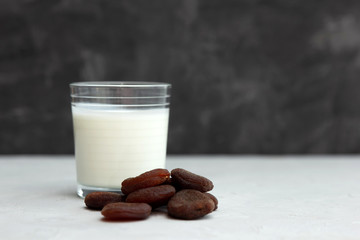 kefir, ayran, homemade yogurt in a glass cup on a gray concrete table. Nearby lies a handful of dried apricots. Snack. Fermented food. Source of pribiotics and vitamins. Place for text