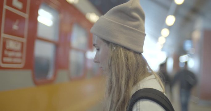 Young woman wearing red jacket standing on the train station and getting ready to enter the train