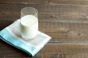 Organic kefir, ayran or milk poured into a glass cup stands on a cotton napkin on a wooden table. Source of Pribiotics. Place for text