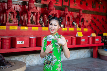 Action portrait an Asian girl wearing Cheongsam green dress. the celebration of something or chinese new year in a joyful and exuberant way. Festivities and Celebration concept