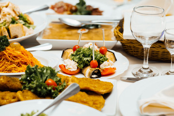 Served dishes to the table for holiday. Cutlery and food on white tablecloths in the restaurant. Design a festive Banquet. Luxurious food for guests and visitors