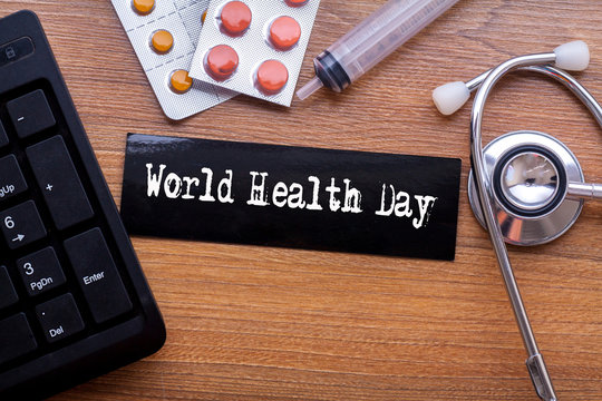 World Health Day words written on label tag with medicine,syringe,keyboard and stethoscope with wood background,Medical Concept