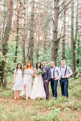 Naklejka na ściany i meble Full length photo of beautiful wedding couple with their friends having fun together, posing on the background of pine forest. Bridesmaids and groomsmen with bride and groom.