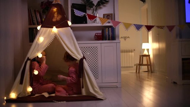 cute happy brothers, kids are playing Rock scissors paper in a teepee in the evening at home