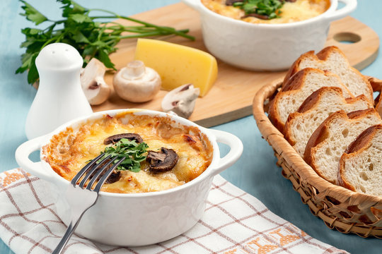 Casserole with chicken, mushrooms and cheese, known in Russia as julienne in white bowl with herbs