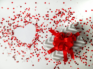 Surprise gift. Red polka dot box with white bow on background with confetti. heart. the view from the top
