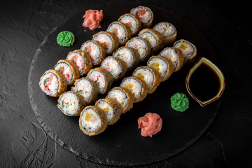 Sushi set with fresh ingredients on black background. Different types of hot fried rolls. Sushi menu. Japanese food. 