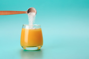 Orange juice with spoon of protein or collagen. Food supplement concept - 311441434
