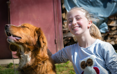 Happy smiling girl having fun with her golden retriever dog on a beautiful sunny day.