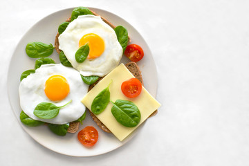 Sandwich with spinach, eggs, tomato and cheese on a white plate. The concept for healthy food, dietary and weight loss program. Selective focus. Copy space is on the right side. 