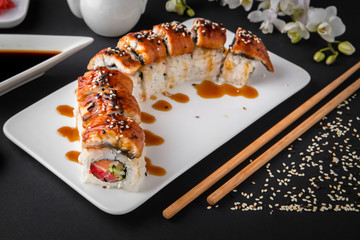 The Luxury Unagi Rol roll with a large slice of smoked salmon in a sauce, with fresh salmon, tuna, Philadelphia cheese, tobiko caviar, cucumber and avocado. Sushi menu. Japanese food. Asian Food
