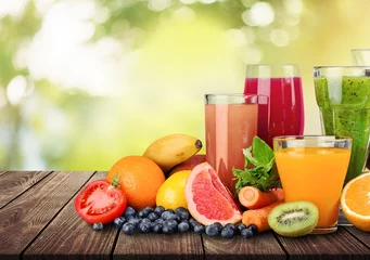 Schilderijen op glas Composition of fruits and glasses of juice on blurred natural background © BillionPhotos.com