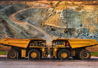 Yellow dump truck loading minerals copper, silver, gold, and other  at mining quarry.