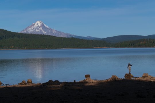 A View Of Mt. Hood Looking Across Timothy Lake. A Fishter Man Cast His Line Into The Lake In The Lower Corner Of The Photo.