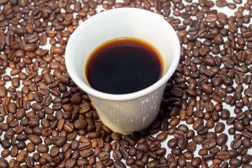 cup with very strong coffee and with the coffee beans making the composition and the background of the photo.