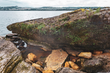 Hot spring breaks through stones against the backdrop of Lake Taupo