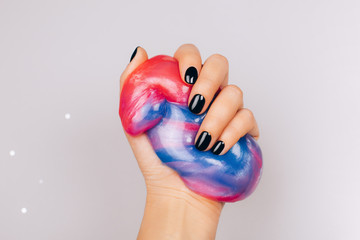 hands with black manicure holding slime in blue and pink vibrant colors - 311449046