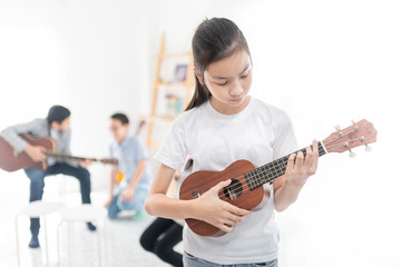 cute asian children playing ukulele, she learning and training music education in her room, she feeling happy and smile in training time
