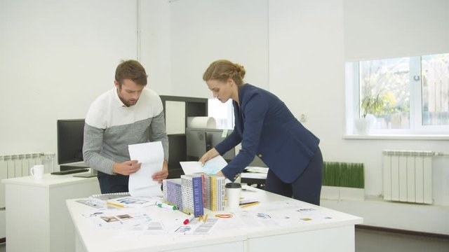 Man and woman pack all schemes of houses from the table