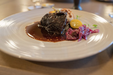 tender roast beef dinner plated with pickled radish and yellow tomato