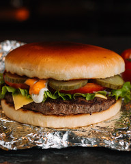 Big sandwich - hamburger burger with beef, pickles, tomato and tartar sauce on black background.
