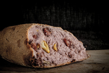 Wine flavoured bread (pain au vin) with its typical red inside, stuffed with walnuts, on display on a wooden plank. it is a typical old French snack