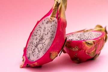 Colorful fruits pattern with Pitahaya tropic fruits, two halfs of fruit on a pastel pink background, copy space