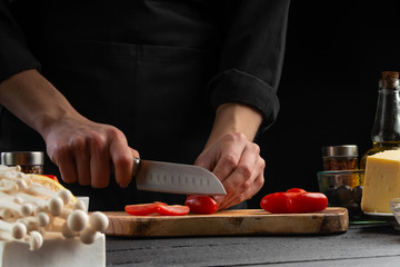 Cook on a wooden board slices cherry tomatoes, close-up, macro. Salad, organic ingredients and...